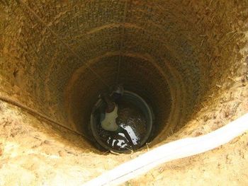 A recharge well has been dug, and after the ring is placed properly, a worker is untying the ropes tied to the ring.